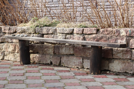 Wooden bench in the yard against the background of a brick wall.の写真素材