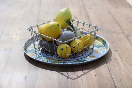 Still life of yellow lemons on a plate on a sunny day on a wooden table. High quality photoの写真素材