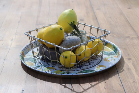 Still life of yellow lemons on a plate on a sunny day on a wooden table. High quality photoの写真素材