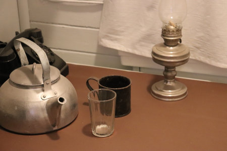 A vintage teapot and glass mug and an old lamp are on the table. High quality photoの写真素材