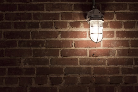 Creepy light bulb on textured red brick wallの写真素材