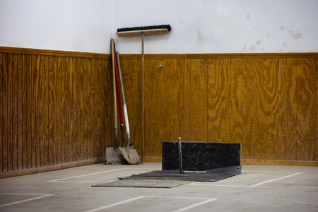 An indoor horseshoe pole with shovels and broom in rearの写真素材