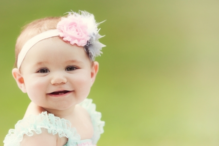 A Japanese-American toddler girl smiles at the camera outsideの写真素材