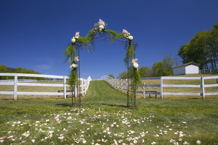 Outdoor ceremony floral archway with petals in the grass. Farm venue set up for wedding day.の写真素材