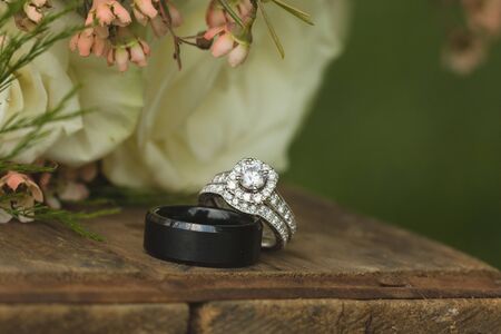Close up macro of bridal diamond wedding band and engagement ring placed by brides floral bouquetの写真素材