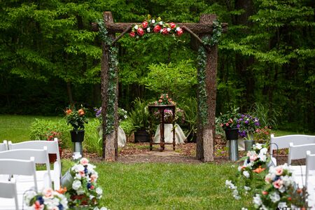 Outdoor summer wedding venue path before the ceremony setup with flowers and wooden archwayの写真素材