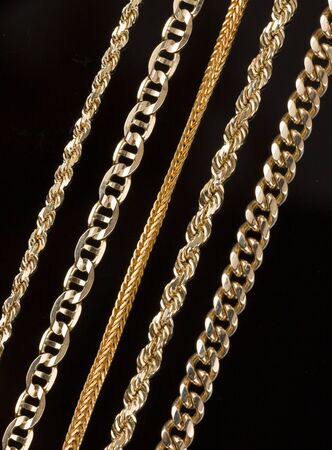 Variety of five gold necklaces close up showing detail of different chains and styles. Black backgroundの写真素材