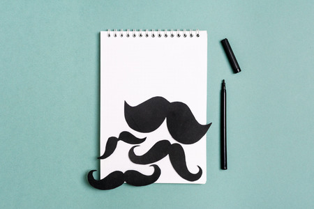 Black paper mustache and glasses on a notepad with a felt-tip pen Mock up Flat lay Copy space