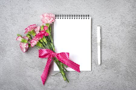 colorful bouquet of different pink carnation flowers, white notebook, pen on on gray concrete background Top view Flat lay Holiday card 8 March, Happy Valentine's day, Mother's day concept Mock up.の写真素材