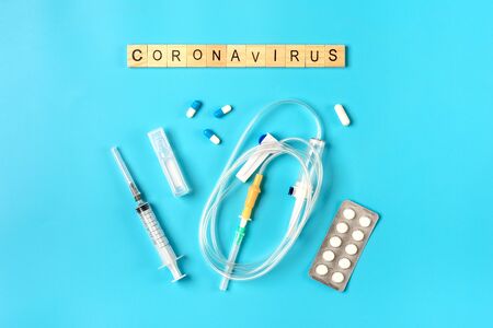 System for droppers, injection syringe, pills, cough syrup on blue background. Coronavirus word. Treatment, prevention, vaccination against coronavirus concept Top view Flat lay.の写真素材