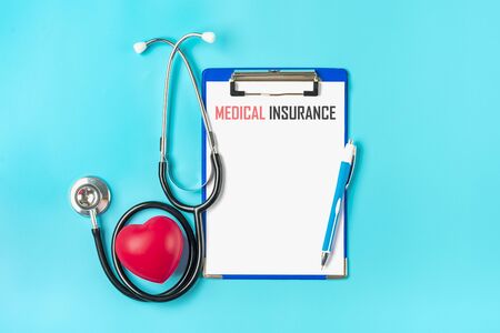 Phonendoscope, heart, tablet with white paper, pen, medicine on blue background Health, life, Medical Insurance concept Top view Flat lay Mock up.の写真素材