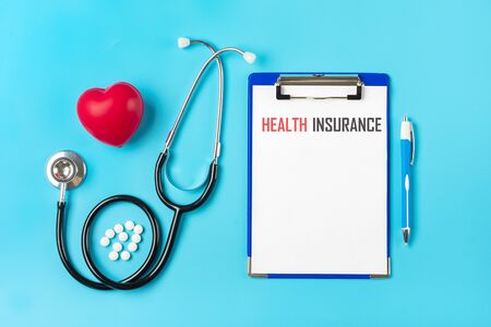 Phonendoscope, heart, tablet with white paper, pen, medicine on blue background Health, life, Medical Insurance concept Top view Flat lay Mock up.の写真素材