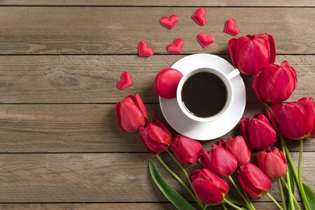Row of red tulips, cup of black coffee americano on wooden background. Space for text, message. Mother's Day, Hello spring, good morning concept. Card. Flat lay. Top view. Rustic style.の写真素材