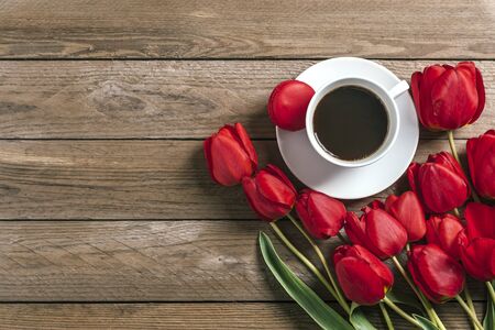 Row of red tulips, cup of black coffee americano on wooden background. Space for text, message. Mother's Day, Hello spring, good morning concept. Card. Flat lay. Top view. Rustic style.の写真素材