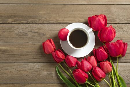 Row of red tulips, cup of black coffee americano on wooden background. Space for text, message. Mother's Day, Hello spring, good morning concept. Card. Flat lay. Top view. Rustic style.の写真素材