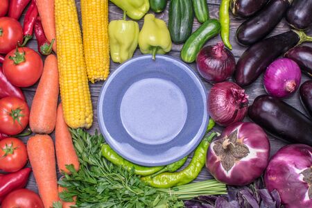 tabletop arrangement of a variety of fresh fruits and vegetables sorted by colors - pepper, tomato, corn, carrot, green salad, cilantro, eggplant, cucumber, basil, dill, onion. Healthy food concept.の写真素材