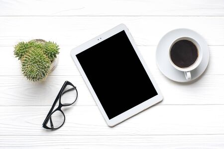 Flat lay home office workspace. Tablet, glasses, cup of coffee, succulent on white wooden background. Top view Business, freelance work concept.の写真素材