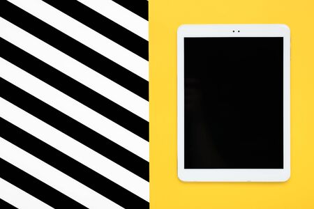 digital tablet with black touch screen display on yellow and white, black stripes background Flat lay Top view Mock up Creative modern composition.の写真素材
