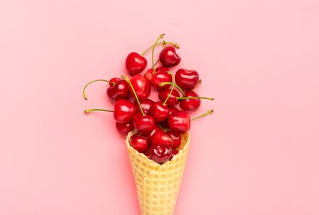 Fresh cherries in waffle cones Ice cream cone filled with fresh sweet cherry on lilac background. Top view. Copy space. Summer creative concept Flat lay Healthy food.の写真素材