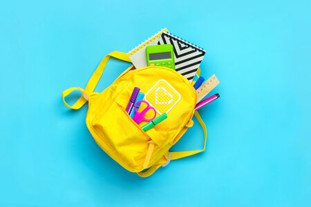 Back to school, education concept. Yellow backpack with school supplies - notebook, pens, ruler,...