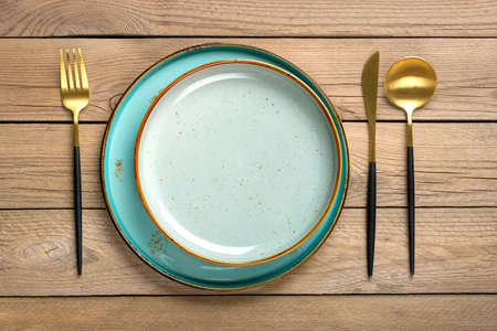 empty double round blue and gray plate, fork, knife, spoon on wooden table Top view Flat lay Dishes...