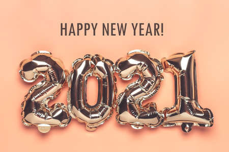 Gold foil balloons numeral 2021 isolated on beige background Flat lay creative composition Top view...