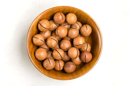 natural organic macadamia nuts in wooden bowl on gray concrete background Flat lay Top view Healthy...