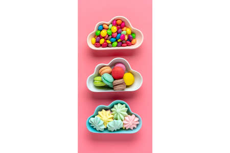 colorful candies - lollipops, meringues, macaroon in bowl in shape of cloud isolated on pink, white...