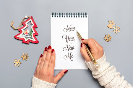 female hand holds pen and writes New Year, New Me on white notepad, tree, snowflake on gray background Top view Flat lay Business motivation, idea, success, vision, inspiration, plan concept.の写真素材