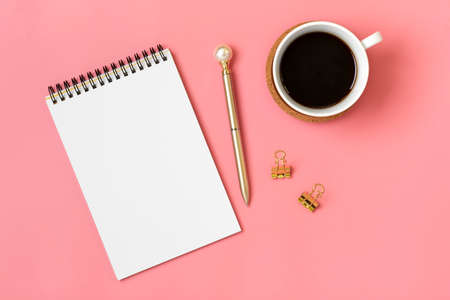 open notepad, cup of coffee, succulents, golden pen on pink background, spiral notebook on table...