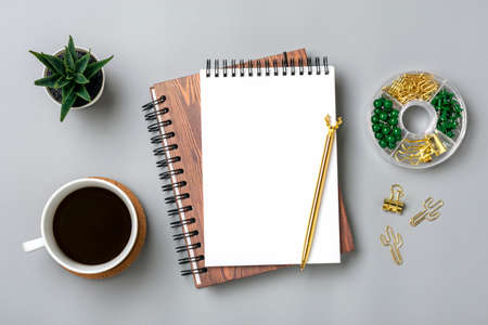 open notepad, cup of coffee, succulents, golden pen on gray background, spiral notebook on table...