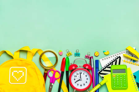 Frame from of office supplies Paper clips, scissors, pens, felt-tip pens, sharpener, backpack, calculator, stapler isolated on green background Flat lay Top view Back to school, education conceptの写真素材
