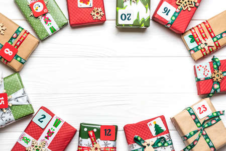 Handmade wrapped red, green gift boxes decorated with ribbons, snowflakes and numbers, Christmas decorations and decor on white table Xmas advent calendar concept Top view Flat lay Holiday cardの写真素材