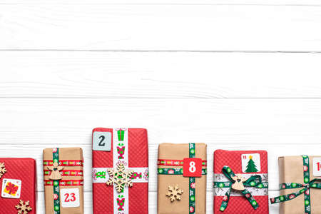 Handmade wrapped red, green gift boxes decorated with ribbons, snowflakes and numbers, Christmas...
