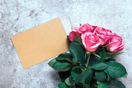 Beautiful pink roses flowers, white notepad on concrete background mock up with copy space for your text. Flat lay, top view Concept of spring, summer and autumn, mother's day, 8 march.の写真素材