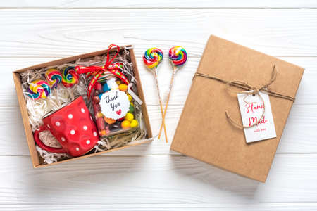 Handmade care package, seasonal gift box with candies, cup on white table Personalized eco friendly basket for family, friends, girl for thanksgiving, xmas, Christmas, mothers, fathers day Flat lay.の写真素材
