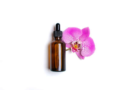glass cosmetic bottle with moisturizing natural oil, purple Orchid isolated on white background Top view Flat lay Eco, bio, zero waste, organic product concept Copy space Mock upの写真素材