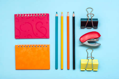 Frame from school and office supplies Paper clips, pencils, sharpener, notepad, stapler isolated on blue background Flat lay Top view Back to school, education concept Mock up Copy space.の写真素材
