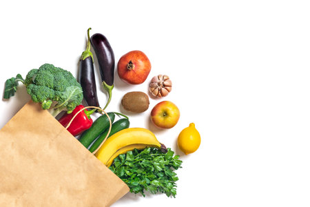 Eco friendly paper shop bag with raw organic green vegetables isolated on white background Flat lay, top view Zero waste, plastic free concept Healthy clean eating diet and detox, agriculture concept.の写真素材