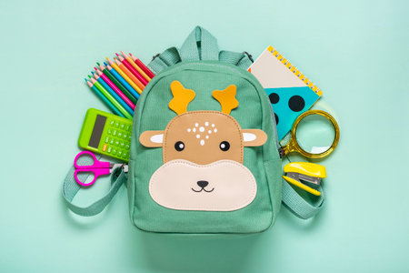 Back to school, education concept Deer backpack with school supplies - notebook, pens, eraser rainbow, numbers isolated on blue background Top view Copy space Flat lay composition Bannerの写真素材