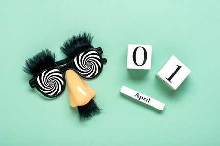 funny face - fake eyeglasses, nose and mustache, calendar date 01 April on green background Happy fools day concept 1st April party Holiday greetind card.の写真素材