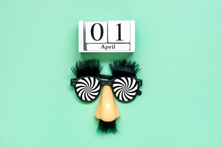 funny face - fake eyeglasses, nose and mustache, calendar date 01 April on green background Happy fools day concept 1st April party Holiday greetind card.の写真素材