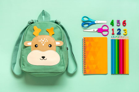 Back to school, education concept Deer backpack with school supplies - notebook, pens, eraser rainbow, numbers isolated on blue background Top view Copy space Flat lay composition Banner.の写真素材