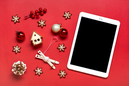 top view tablet with black digital screen, Christmas box and decor on red table Flat lay Holiday shopping list, Happy New Year, online shop, chooses gifts, makes purchases Mockup.の写真素材