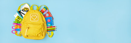 Back to school, education concept. Yellow backpack with school supplies - notebook, pens, ruler,...