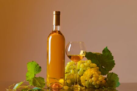 Wine. Bottle and glass of white wine with ripe grapes still life. White wine on a light background. Border art design.の写真素材
