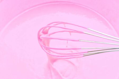 Whipping with a metal whisk of pink cream for baking