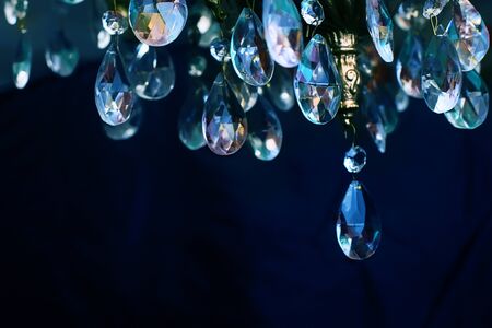 Crystal chandelier close-up. Cold and warm reflections on the edges of the crystal. Dark backgroundの写真素材