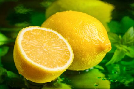 Sliced lemon on a shiny green background with mint and water drops. The cure for seasonal runny noseの写真素材