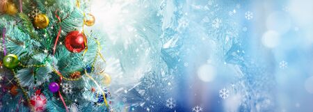 Christmas holiday background, Christmas tree decorated, toys and ribbons on icy blue background.の写真素材